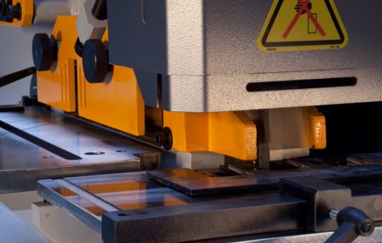 Steelworker mid-operation with only one station set up (e.g., punch station active) while other stations are clearly idle in-frame