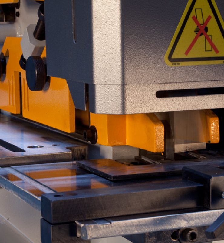 Steelworker mid-operation with only one station set up (e.g., punch station active) while other stations are clearly idle in-frame